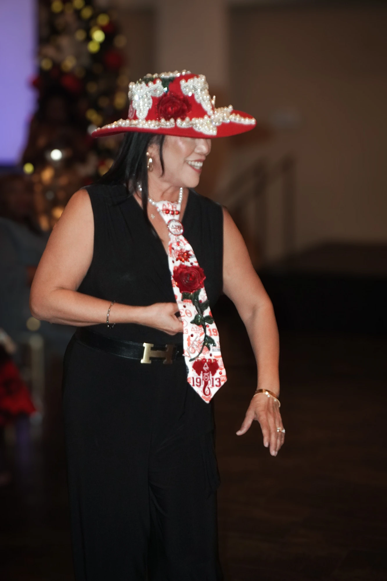 A runway model in a jeweled red hat and rose tie