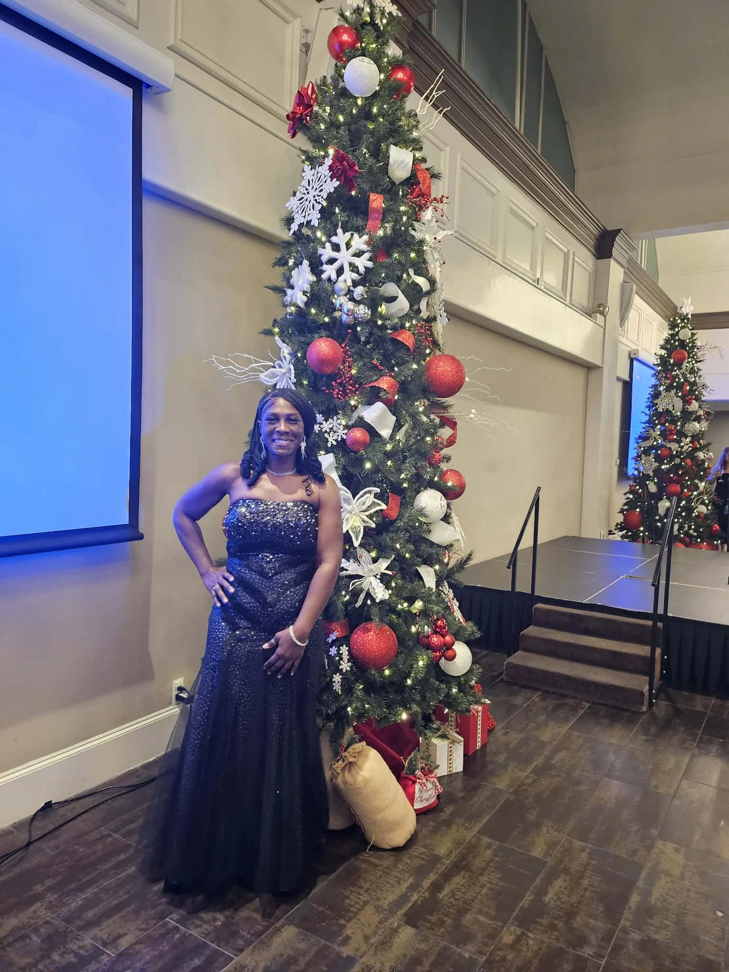 A guest in a navy sequin gown by the Christmas tree